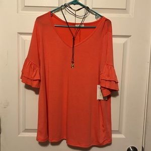 Peach colored shirt with a necklace.